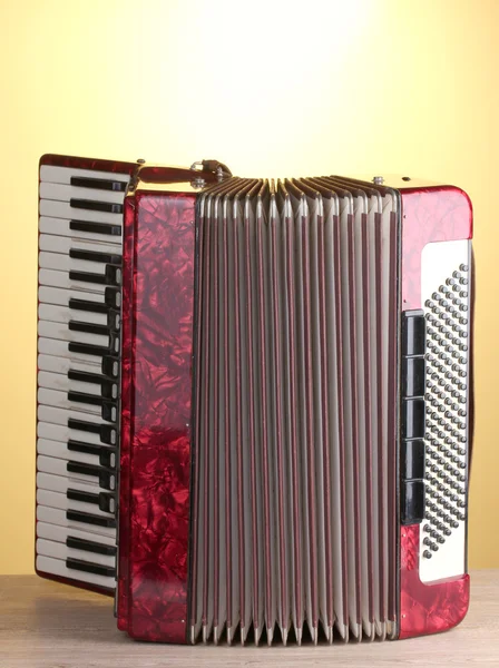 Retro accordion on wooden table on yellow background — Stock Photo, Image