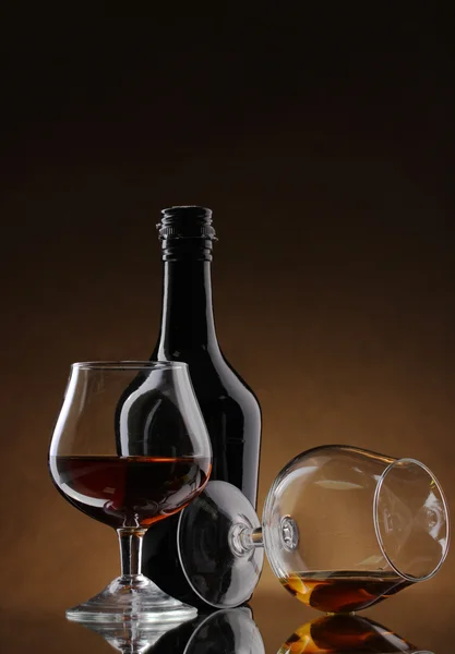 Glazen van brandy en fles op bruine achtergrond — Stockfoto