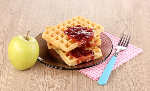 Tasty waffles with jam on plate on wooden background — Stock Photo, Image
