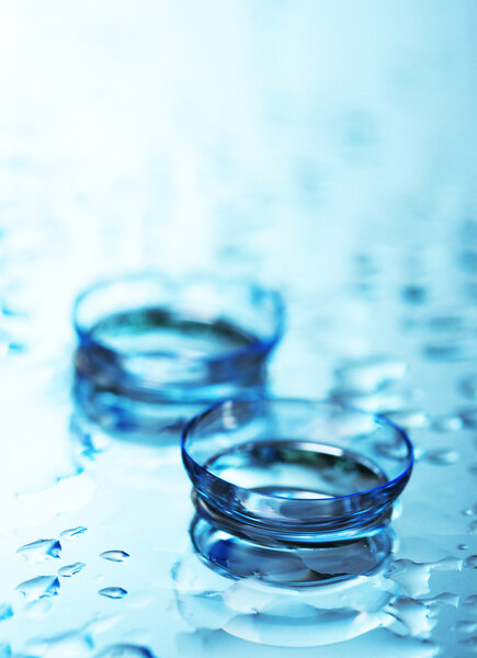 Contact lens with drops on blue background