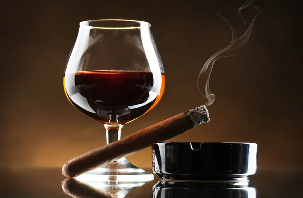 Glas konjak och cigarrer på brun bakgrund — Stockfoto