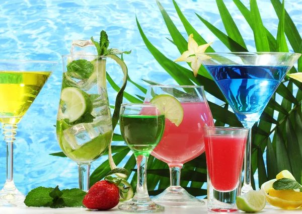 Glasses of cocktails on table on blue sea background — Stock Photo, Image