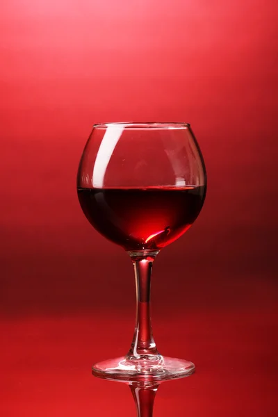 Винное стекло на красном фоне — стоковое фото