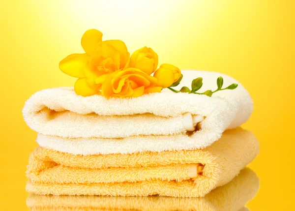Πολύχρωμο πετσέτες και λουλούδια σε κίτρινο φόντο — Φωτογραφία Αρχείου