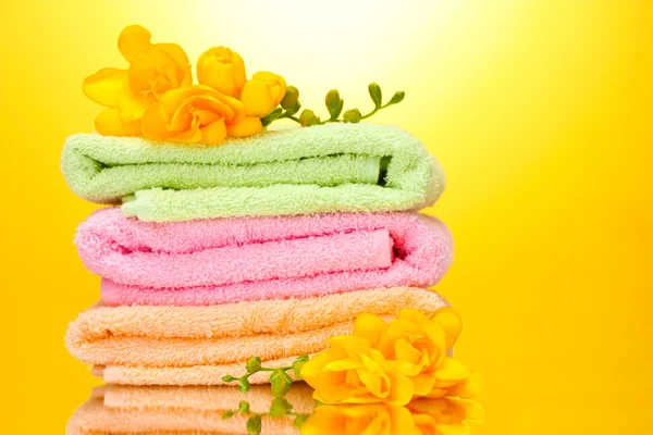 Colorful towels and flowers on yellow background — Stock Photo, Image