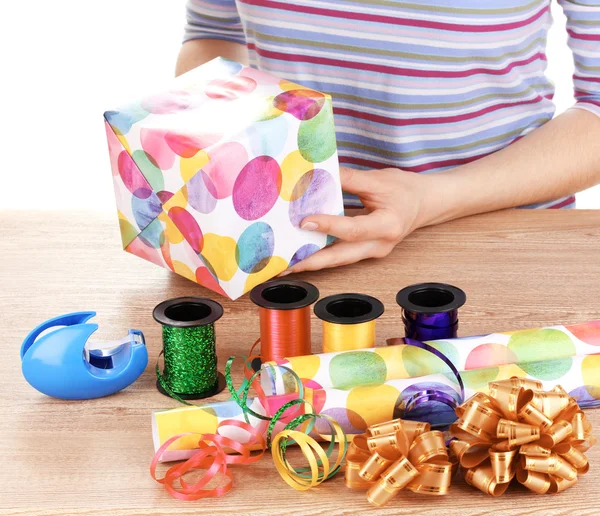 Упаковка подарков в окружении бумаги, ленты и луков — стоковое фото