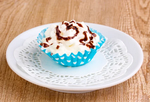 Creamy cupcake on saucer on wooden background — Stock Photo, Image