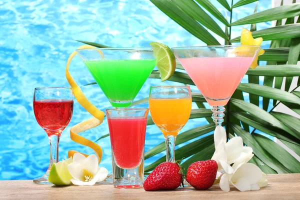 Exotische Cocktails und Blumen auf dem Tisch vor blauem Meeresgrund — Stockfoto