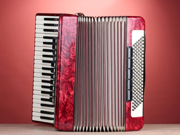 Retro accordion on wooden table on red background — Stock Photo, Image