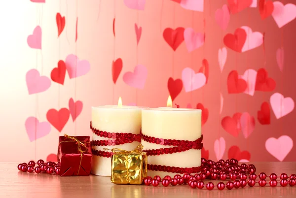 Piękne świece na drewnianym stole na czerwonym tle w stylu romantycznym — Zdjęcie stockowe