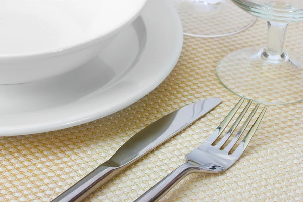 Накрытие стола вилкой, ножом, тарелками и салфеткой — стоковое фото