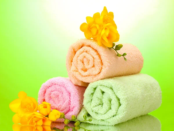 Kleurrijke handdoeken en bloemen op groene gele achtergrond — Stockfoto