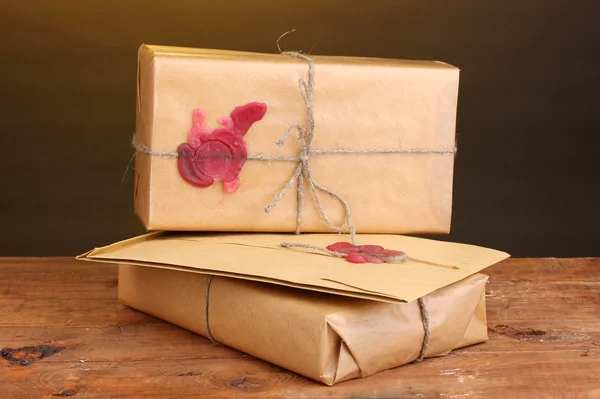 Parcels and envelope with sealing wax on wooden table on brown background Royalty Free Stock Photos