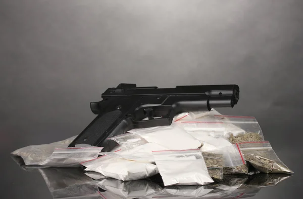 Kokain och marijuana i paket och pistol på grå bakgrund — Stockfoto