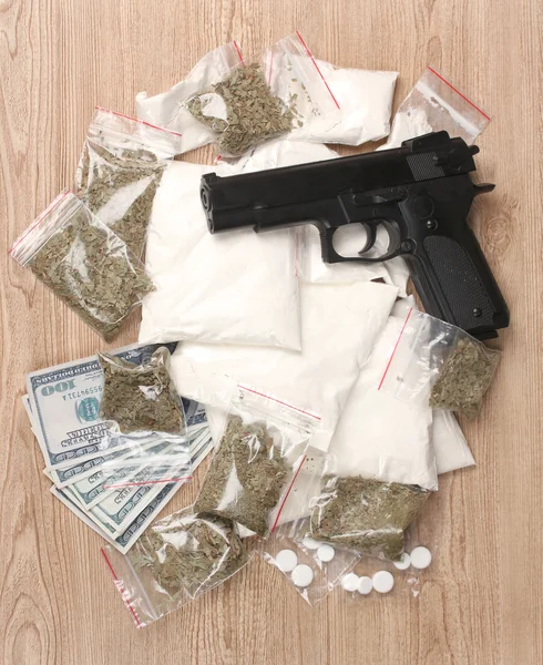 Cocaína y marihuana en paquetes, dólares y pistola sobre fondo de madera —  Fotos de Stock