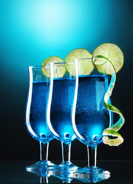 Cocktail bleu dans des verres avec du citron vert sur fond bleu — Photo