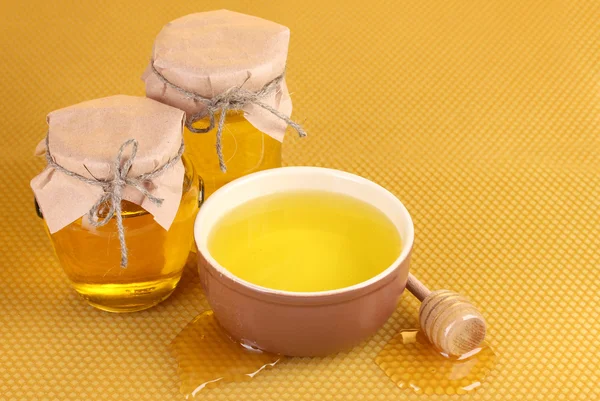 Баночки з медом, миска та дерев'яний мряка з медом на жовтому фоні — стокове фото