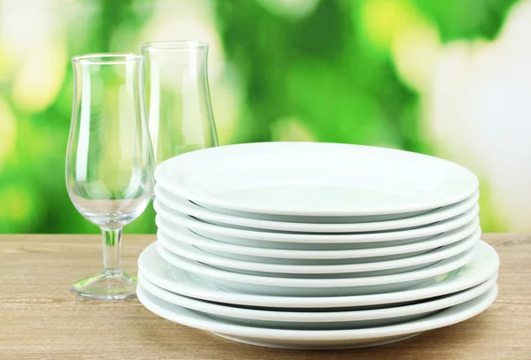 Piatti puliti su tavolo di legno su sfondo verde — Foto Stock