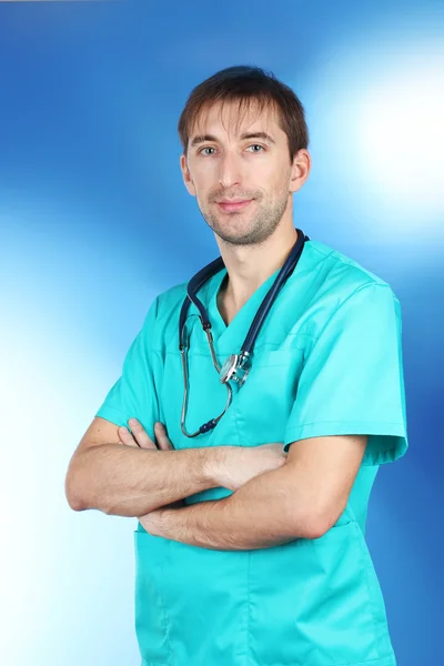 Молодий лікар зі стетоскопом на синьому фоні — стокове фото