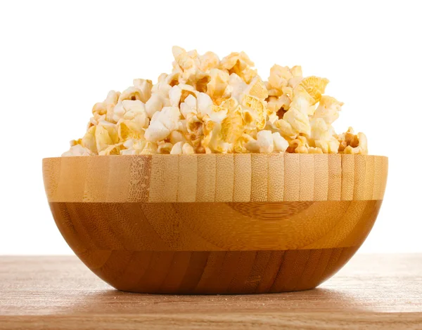 Popcorn in houten kom op houten tafel op witte achtergrond — Stockfoto