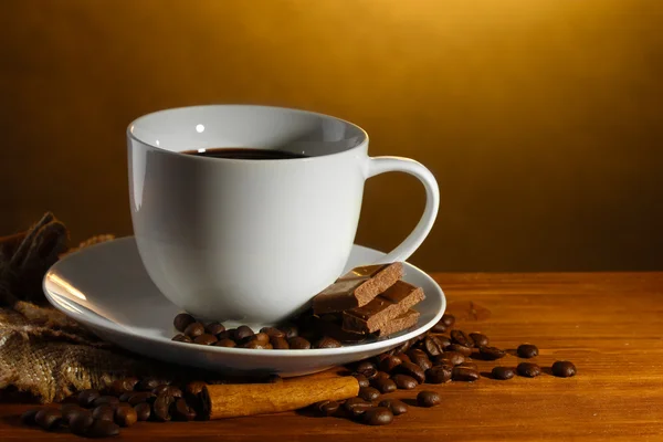 杯咖啡和咖啡豆、 肉桂棒和巧克力棕色背景上的木桌上 — 图库照片
