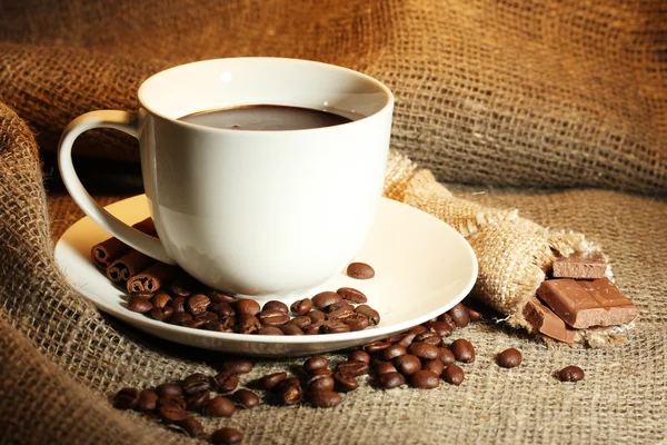 Cup of coffee, beans and chocolate on sacking background — Stock Photo, Image