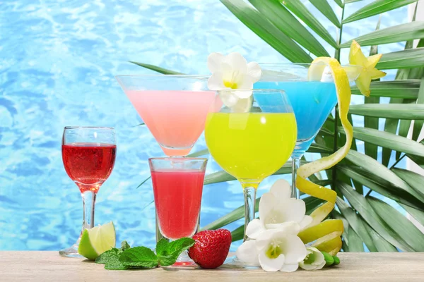 Egzotyczne koktajle i kwiaty na stole na tle błękitnego morza — Zdjęcie stockowe