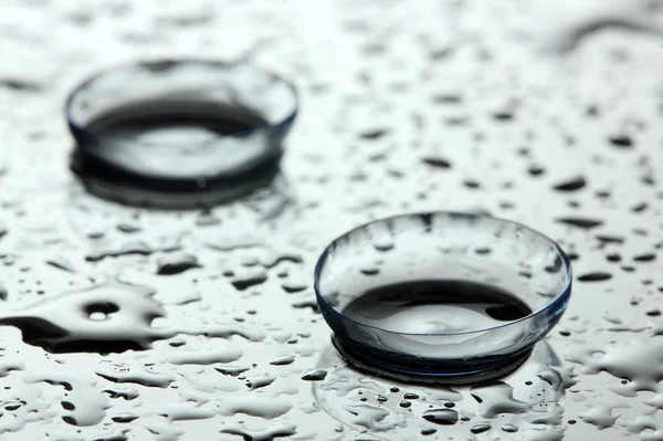 Lente de contato com gotas sobre fundo cinza — Fotografia de Stock