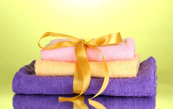 Colorful towels with ribbon on green background — Stock Photo, Image