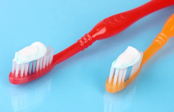 Toothbrushes with paste on blue background — Stock Photo, Image