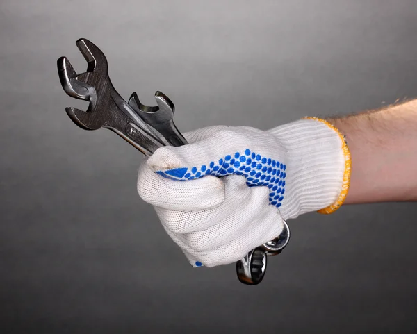Chaves na mão com luva de proteção em fundo cinza — Fotografia de Stock