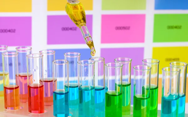 Tubos de ensayo con líquido de color y pipeta sobre fondo de muestras de color —  Fotos de Stock