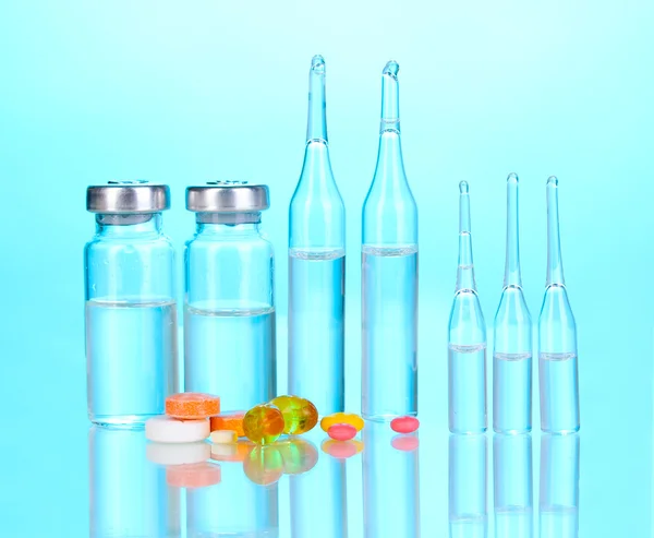 Comprimidos e ampolas sobre fundo azul — Fotografia de Stock