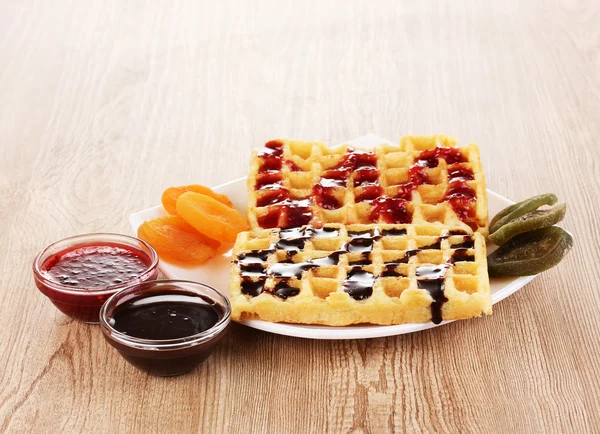 Waffles doces com geléia e chocolate na placa no fundo de madeira — Fotografia de Stock