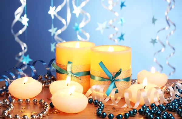 Hermosas velas, regalos y decoración en mesa de madera sobre fondo azul —  Fotos de Stock