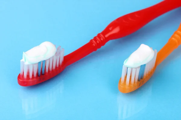 Escovas de dentes com pasta no fundo azul — Fotografia de Stock