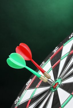 Dart board with darts on green background clipart