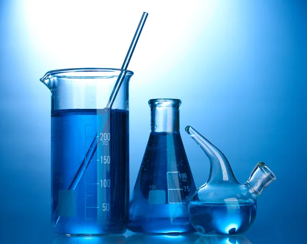 Reagenzgläser mit blauer Flüssigkeit auf blauem Hintergrund — Stockfoto