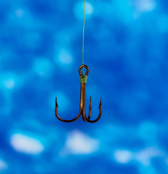Výšek rybářský háček na modrém pozadí — Stock fotografie