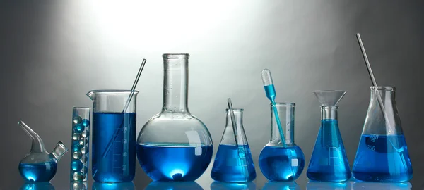 Reagenzgläser mit blauer Flüssigkeit auf grauem Hintergrund lizenzfreie Stockfotos