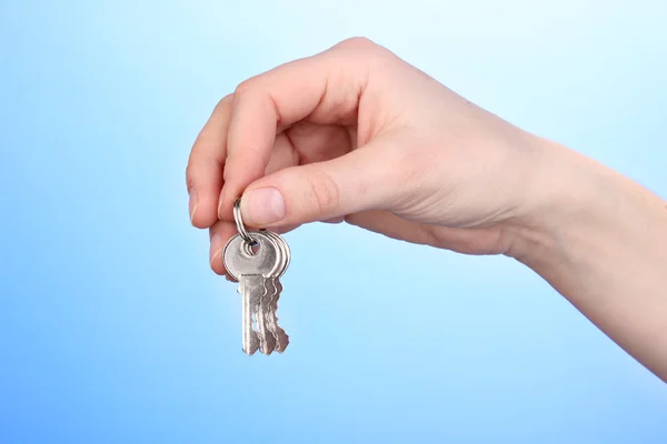 Keys in hand on blue background Stock Photo
