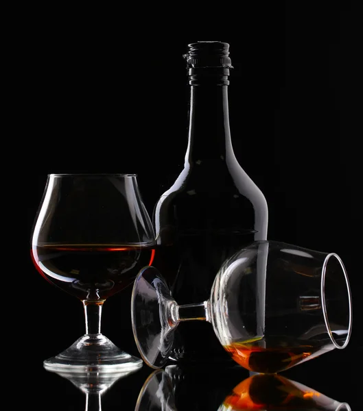 Lunettes de brandy et bouteille sur fond noir — Photo