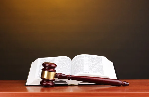 Judge's gavel and open book on wooden table on brown background — Stock Photo, Image
