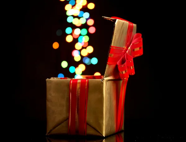 Bokeh arka planı siyah olan altın hediye kutusu açma — Stok fotoğraf