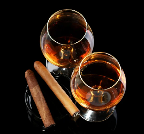 Dos copas de brandy y cigarros sobre fondo negro —  Fotos de Stock