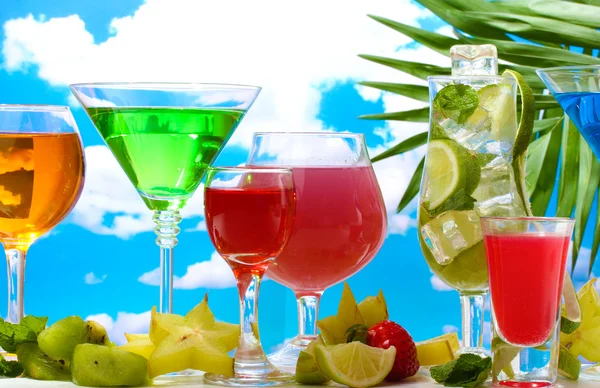 Glasses of cocktails on table on blue sky background — Stock Photo, Image