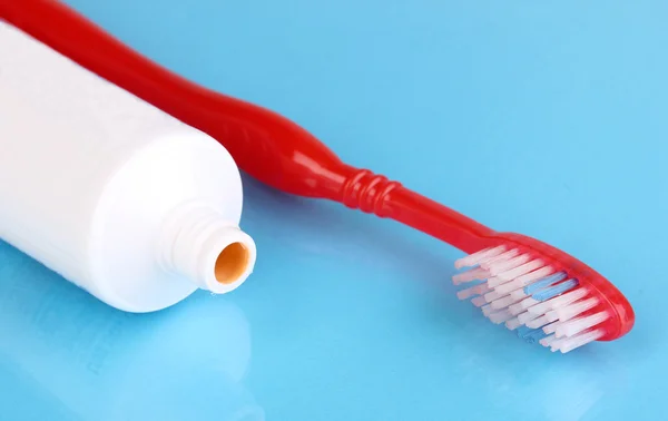 Cepillo de dientes y pasta sobre fondo azul — Foto de Stock