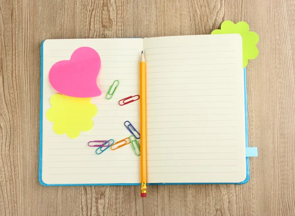 Öppna anteckningsbok med klisterlappar och penna på trä bakgrund — Stockfoto