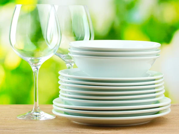 Чистые блюда на деревянном столе на зеленом фоне — стоковое фото