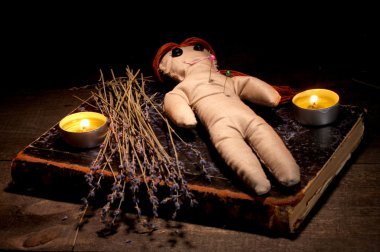 Voodoo doll girl on a wooden table in the candlelight clipart